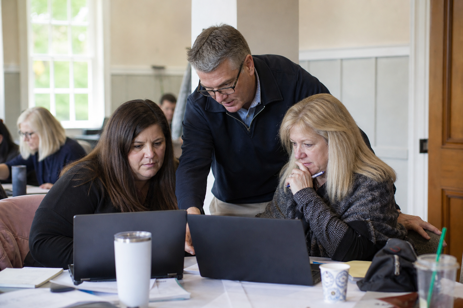 Facilitator helping two workshop participants solve a real administrative workflow